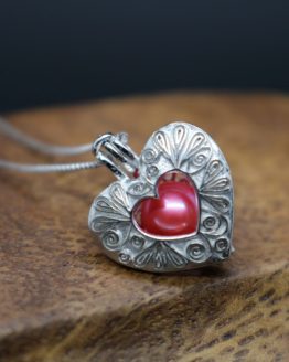 sterling silver heart locket that holds a pearl