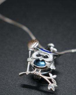 sterling silver owl dressed up as a witch perched on a branch is a locket that holds one pearl.